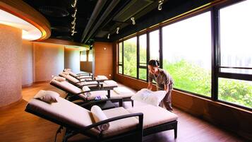 Relax in a serene spa room with a view of lush greenery and the cityscape.