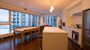 A modern kitchen with a central island, wooden dining table, and chairs. - Snow Crystal (Kutchan)