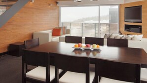Un comedor moderno con techo de madera, un ventanal grande y un televisor de pantalla plana en la pared.