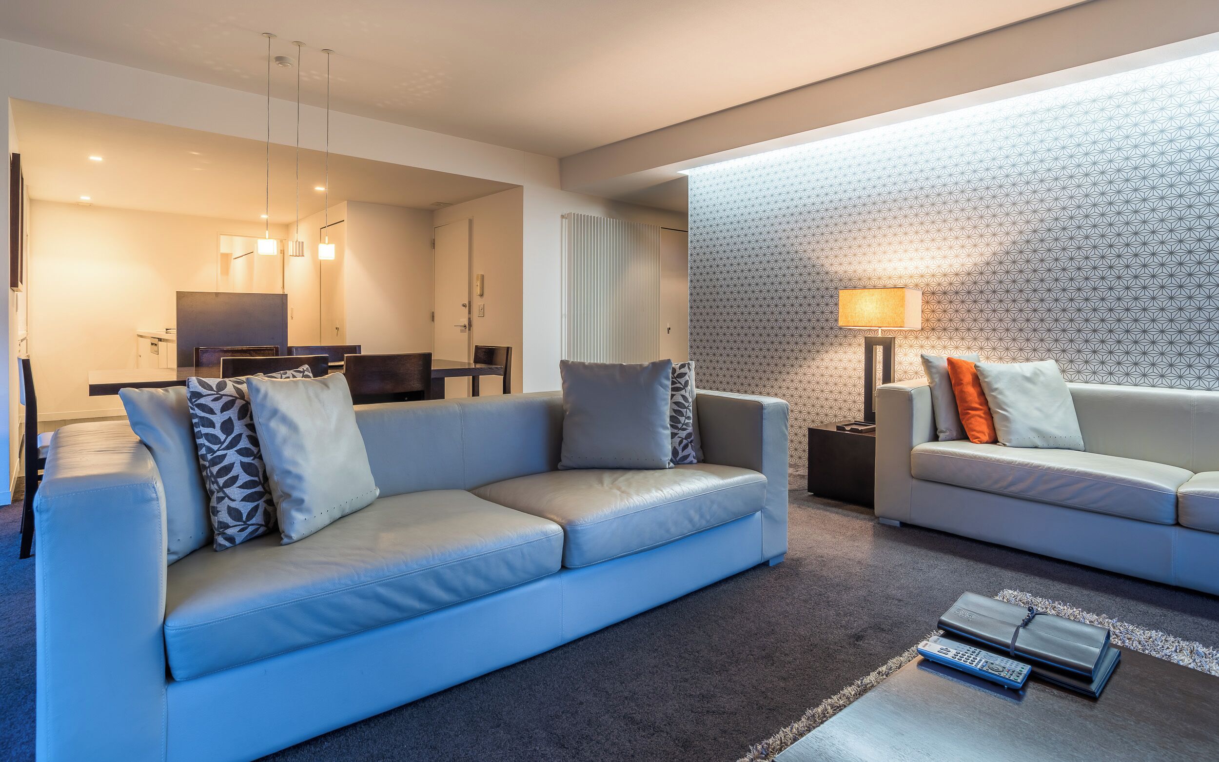 A modern living room with two sofas, a coffee table, and a dining area with a table and chairs.