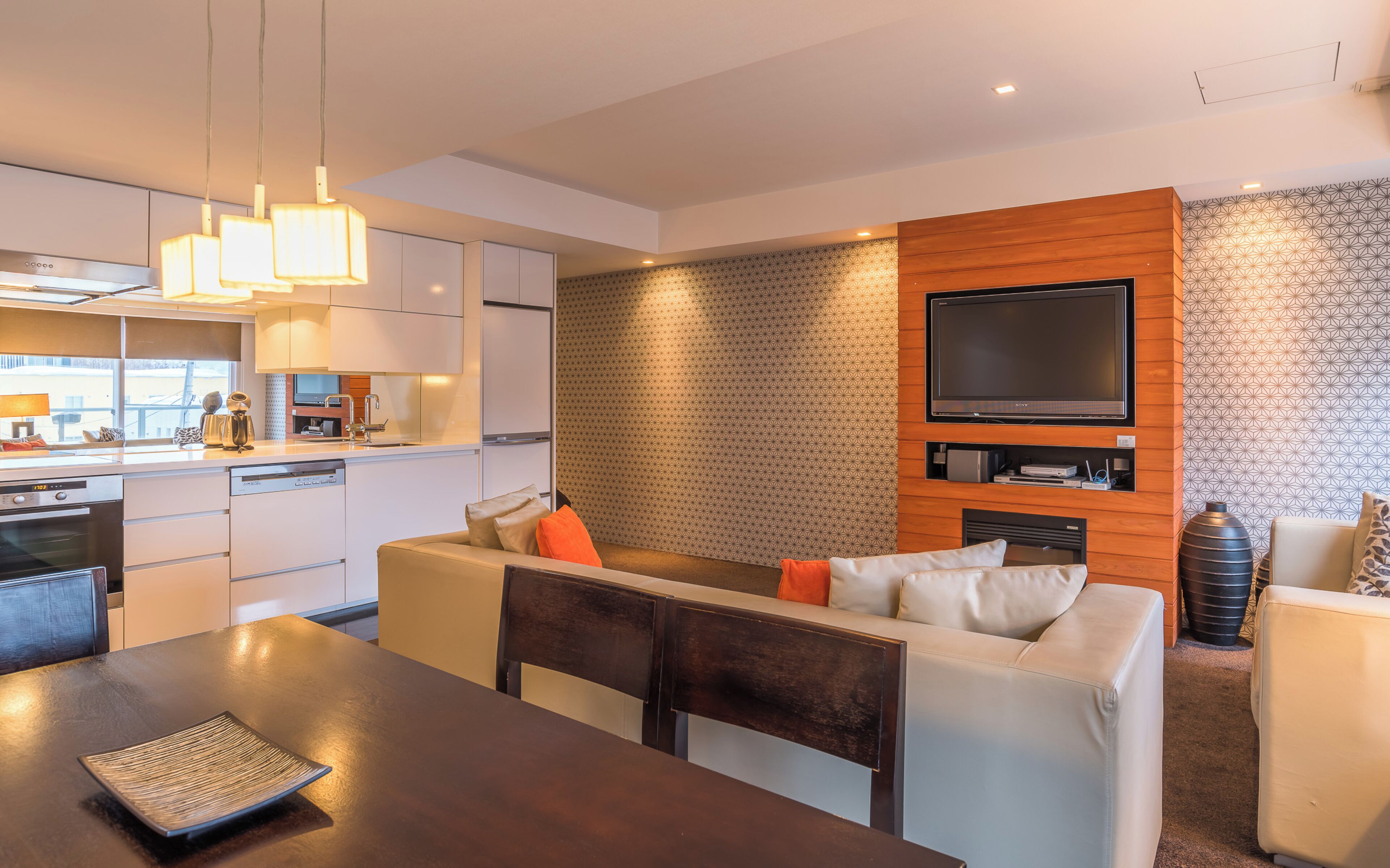 A modern living room with a sofa, dining table, and kitchen area.
