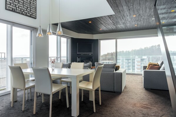 Un salon moderne avec un coin repas, de grandes fenêtres et une vue sur la ville.
