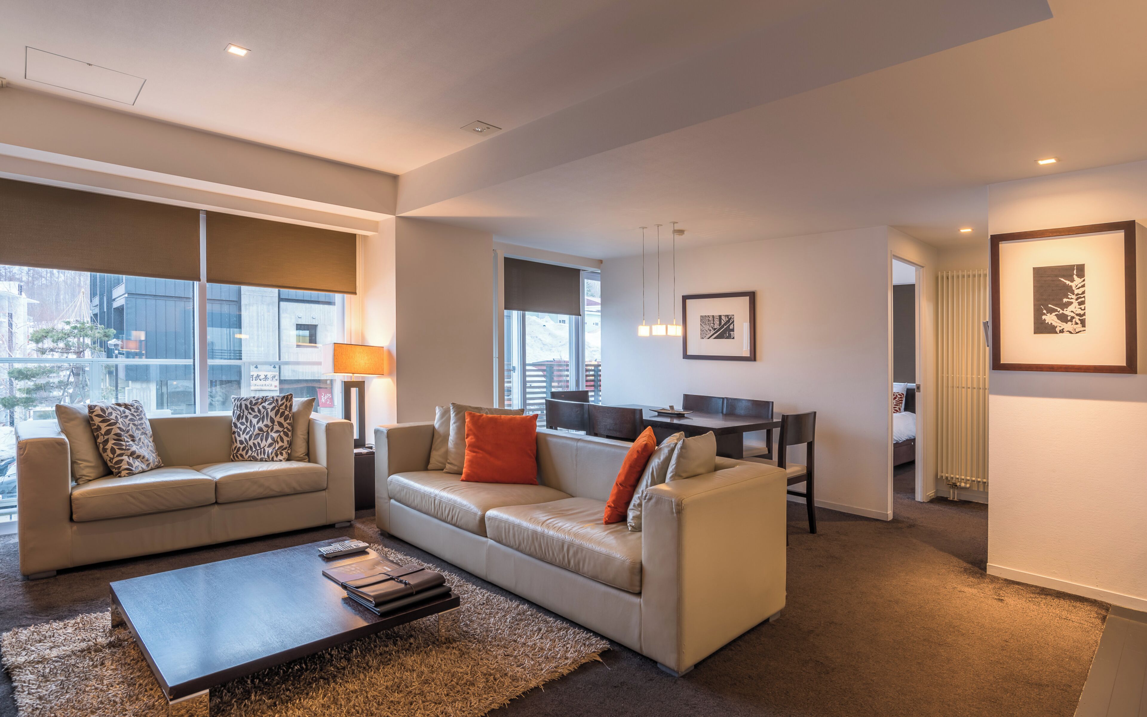 A modern living room with two sofas, a coffee table, and a dining area with a table and chairs.