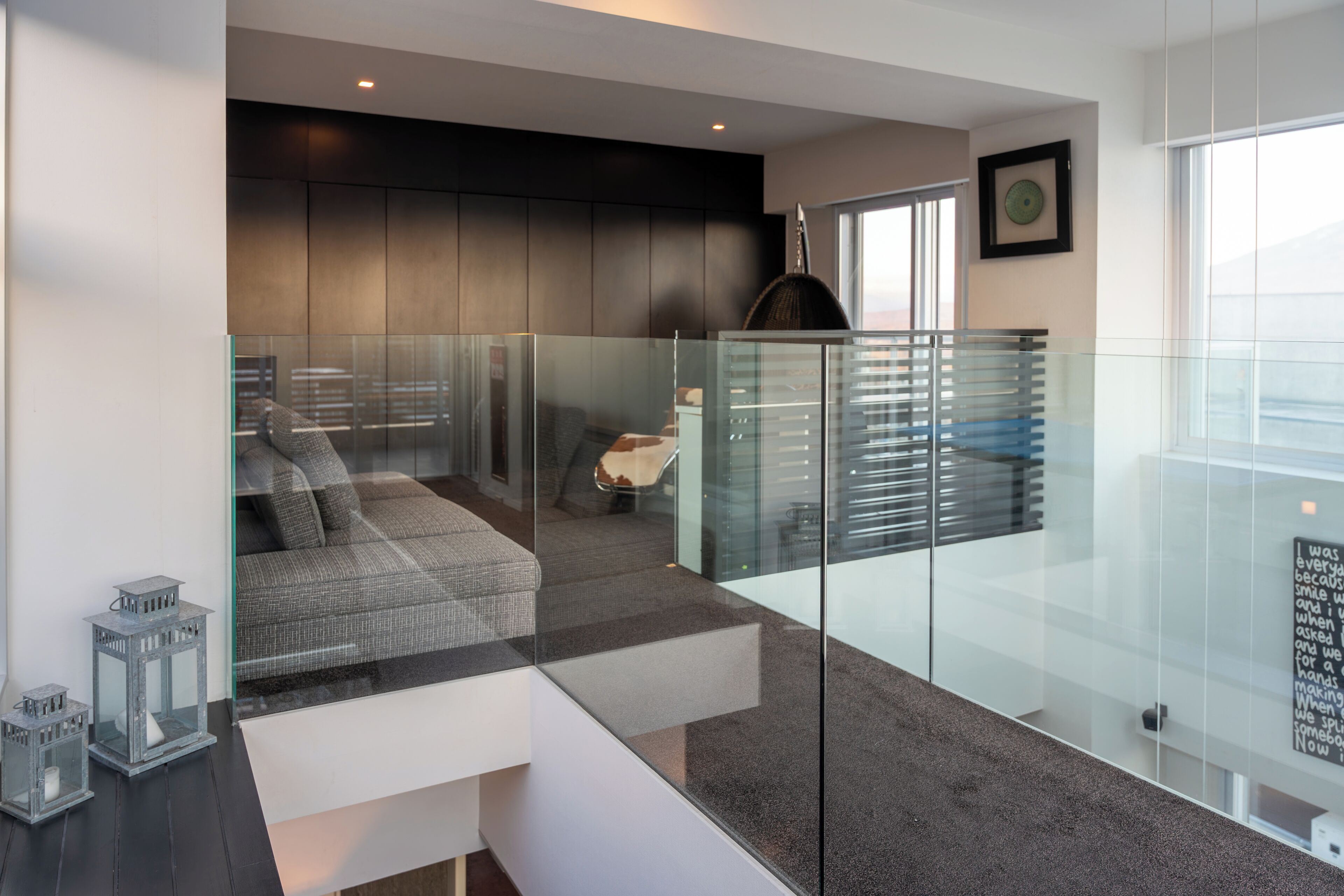 A modern hotel room with a glass partition, a sofa, and a view of the city.