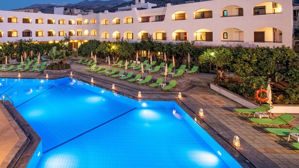 A hotel with a swimming pool, multiple balconies, and a landscaped garden area.