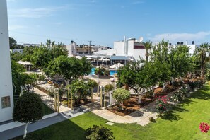 A residential area with a swimming pool, outdoor seating, and lush greenery. - Malia Holidays Hotel (Hersonissos)