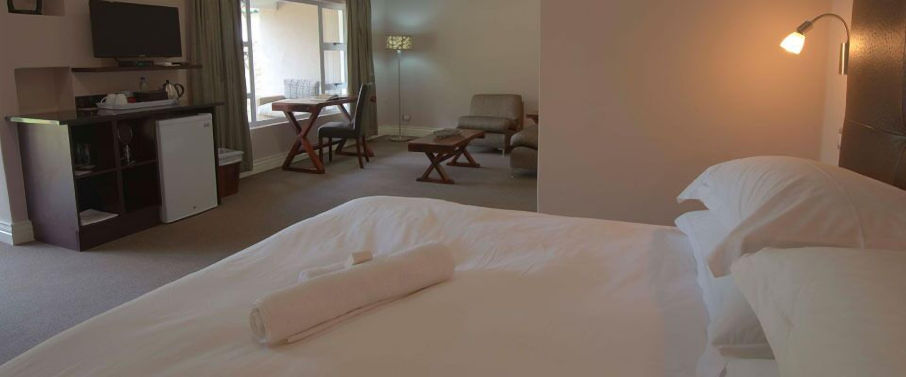 A hotel room with a bed, a desk, a chair, a sofa, and a television.