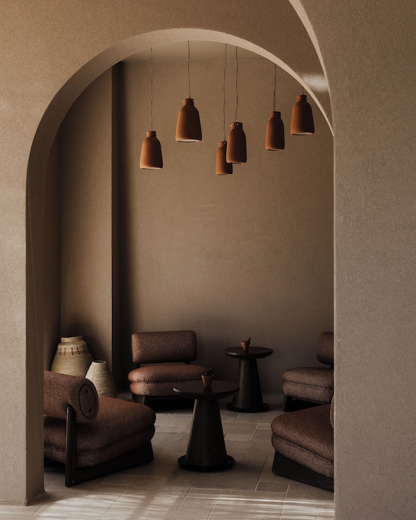 A modern interior with a seating area, a coffee table, and hanging pendant lights. - Momi Slow Living Hotel (Hersonissos)