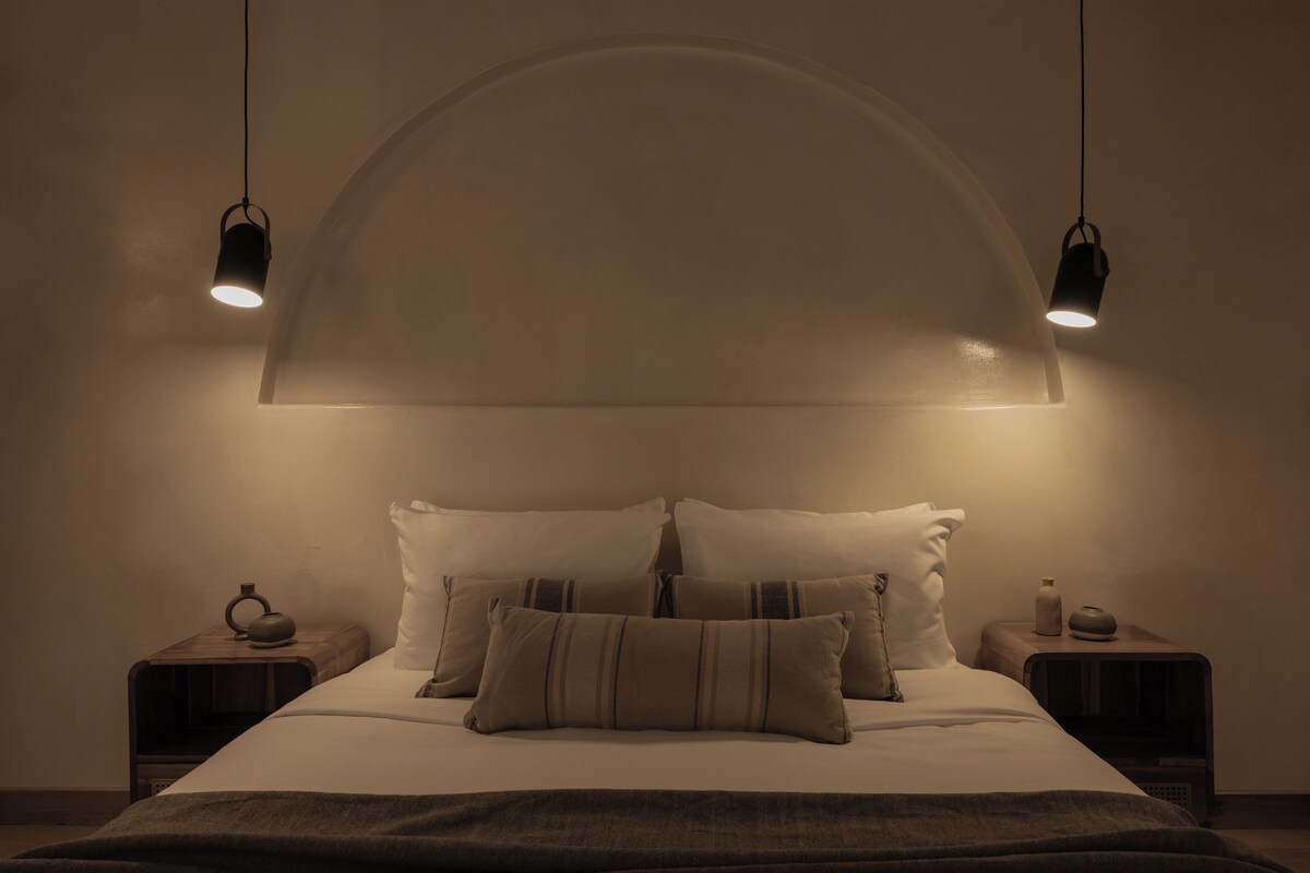 A bedroom with a bed, two bedside tables, and a large arched ceiling.