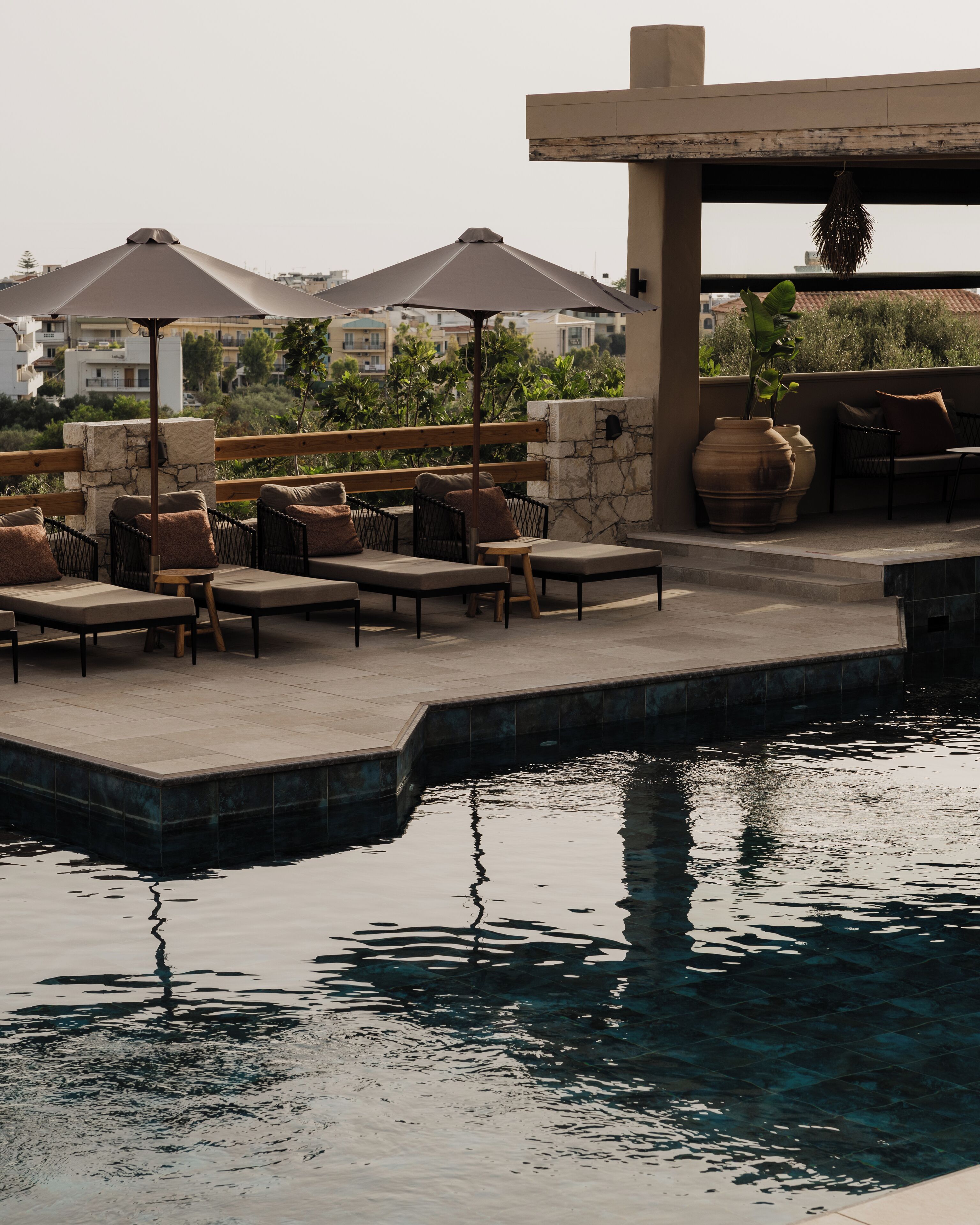 A poolside area with lounge chairs, umbrellas, and a stone wall.