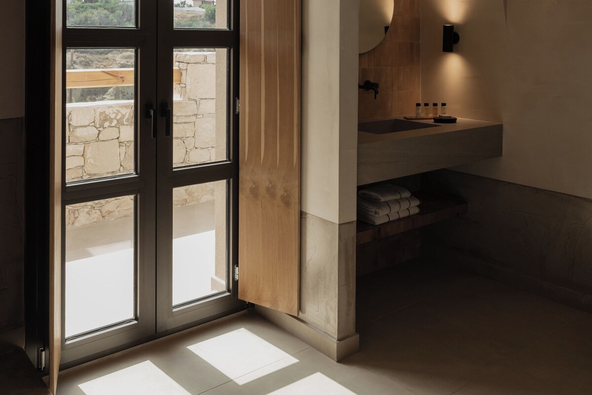 A modern bathroom with a large window, a sink, and a mirror.
