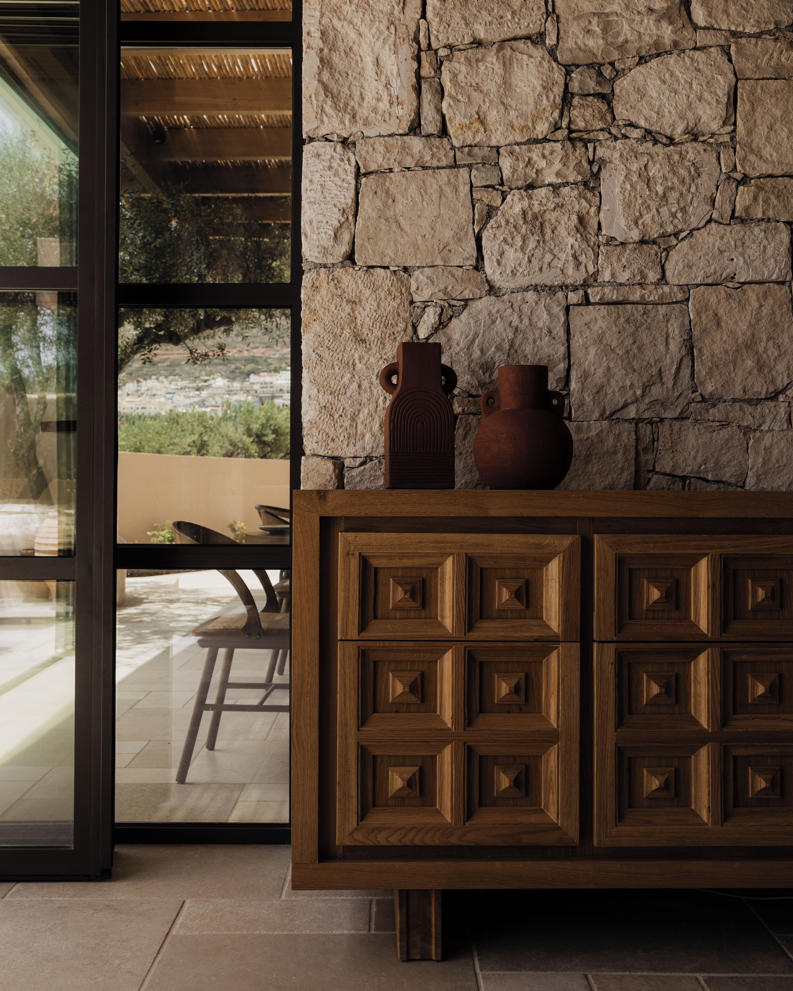 A stone wall with two vases on a wooden cabinet.