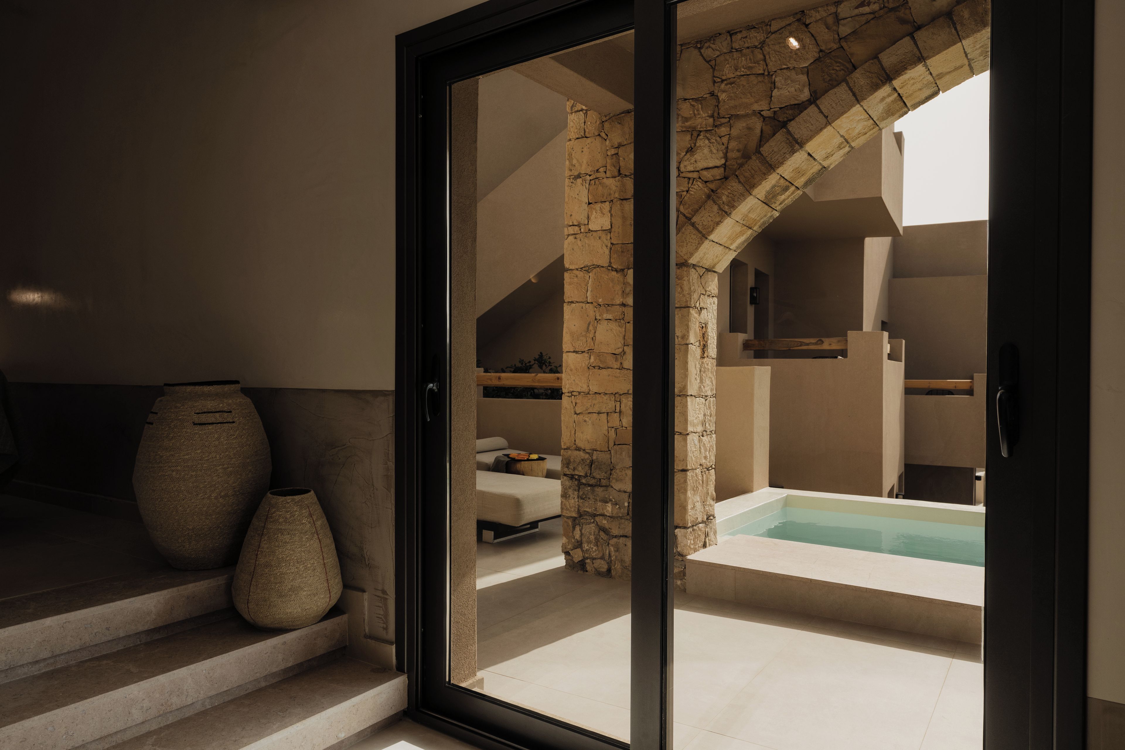 Ein modernes Interieur mit einem steinernen Bogen, der zu einem Badezimmer mit Badewanne führt.