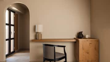 A minimalist room with a wooden desk, a chair, a lamp, and a cabinet.
