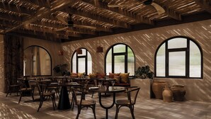 A spacious dining area with multiple tables and chairs, large windows, and a modern ceiling design. - Momi Slow Living Hotel (Hersonissos)