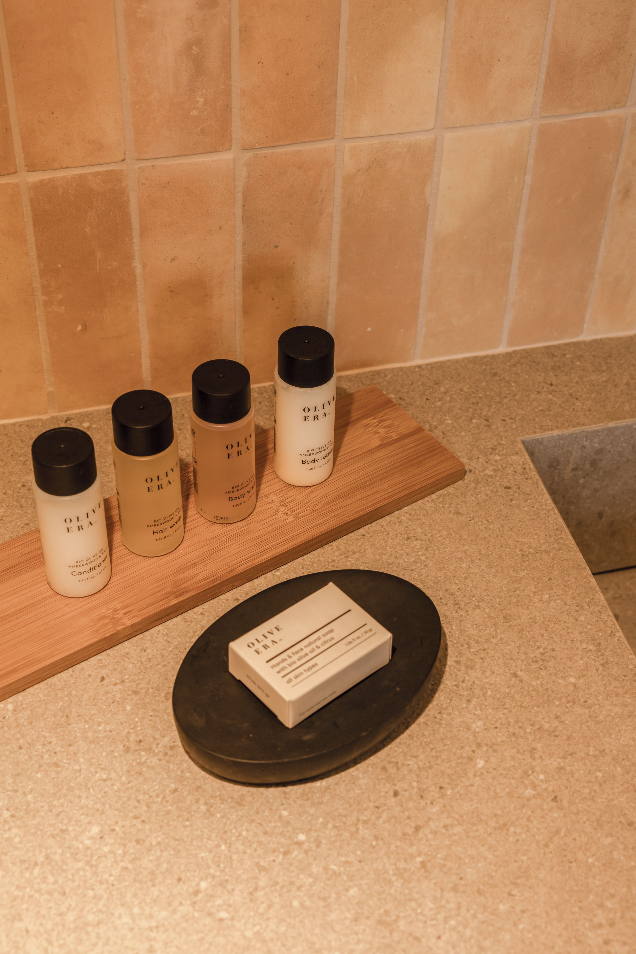 Una encimera con cuatro botellas de loción corporal y una caja de crema para manos y rostro.
