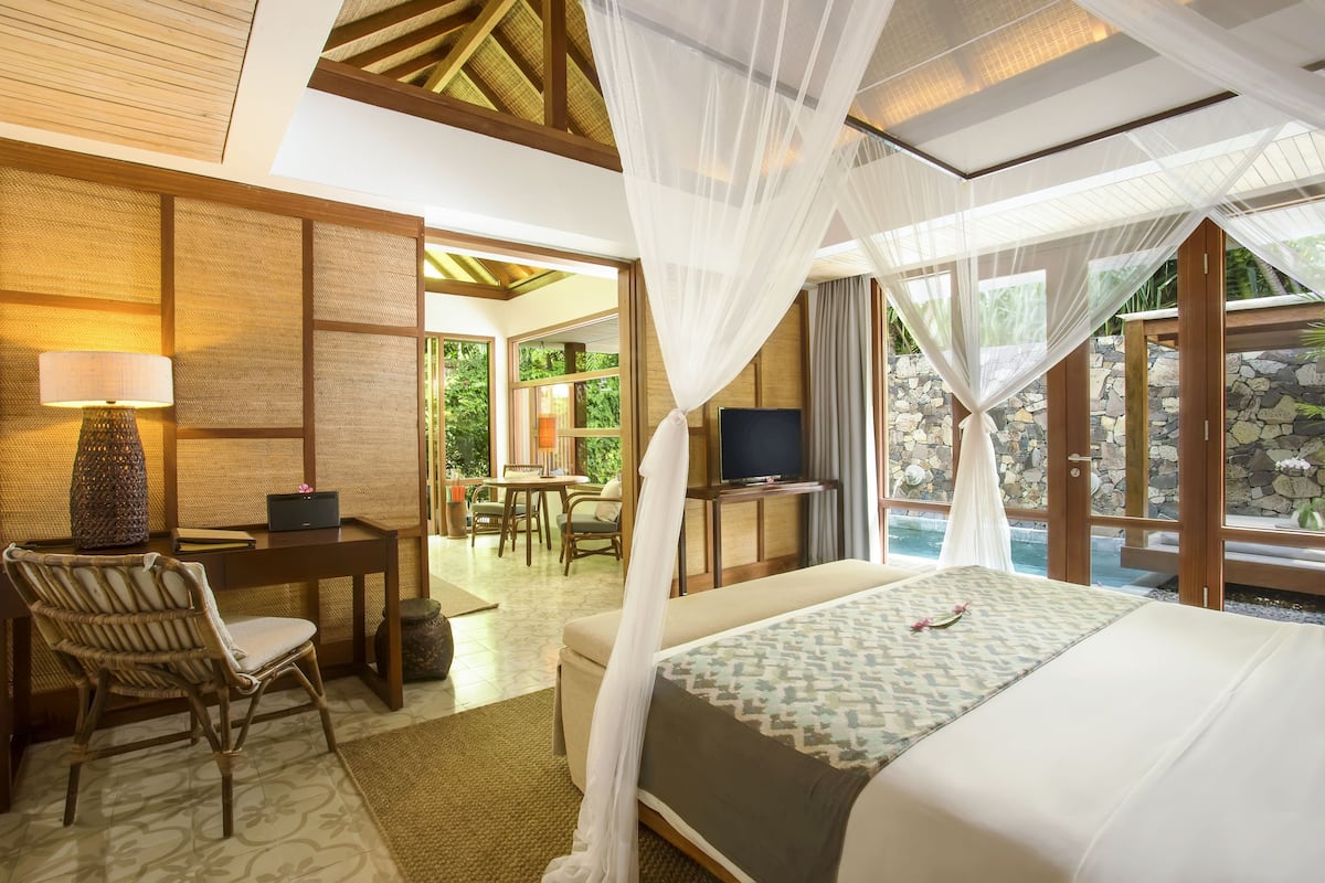 A hotel room with a bed, a desk, a chair, a television, and a view of the outdoors.