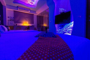 Una habitación de hotel con una cama, un televisor en la pared y un acuario grande.