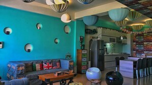 A modern living room with a teal wall, round mirrors, a sofa with British flags, a coffee table, and a kitchen area with a refrigerator and cabinets. - F One B&B (Wujie)