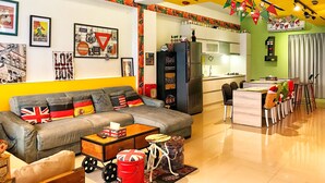 A modern living room with a grey sofa, a wooden coffee table, and a kitchen area with a fridge and dining table. - F One B&B (Wujie)