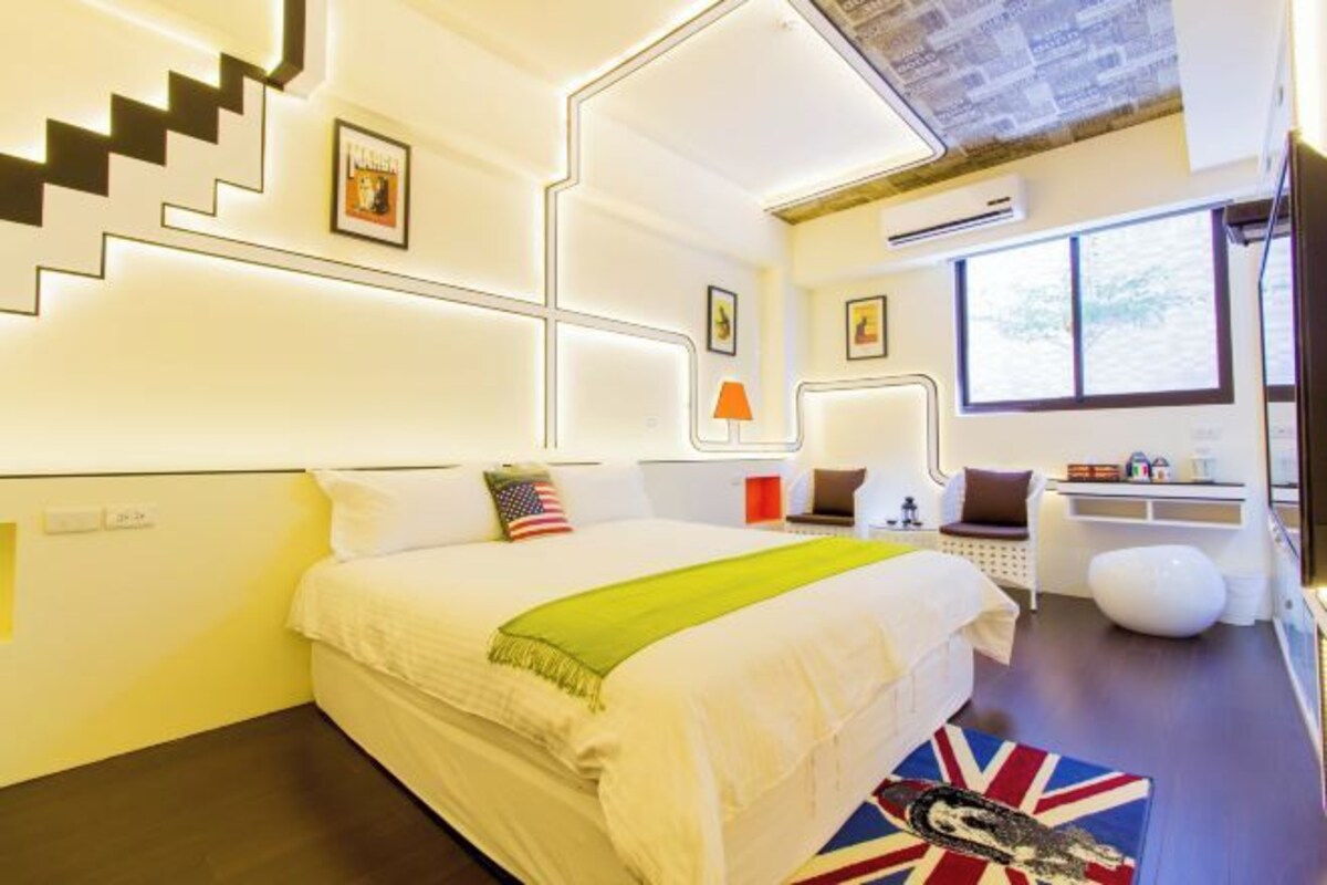 A modern hotel room with a large bed, a desk, and a view of the outdoors.