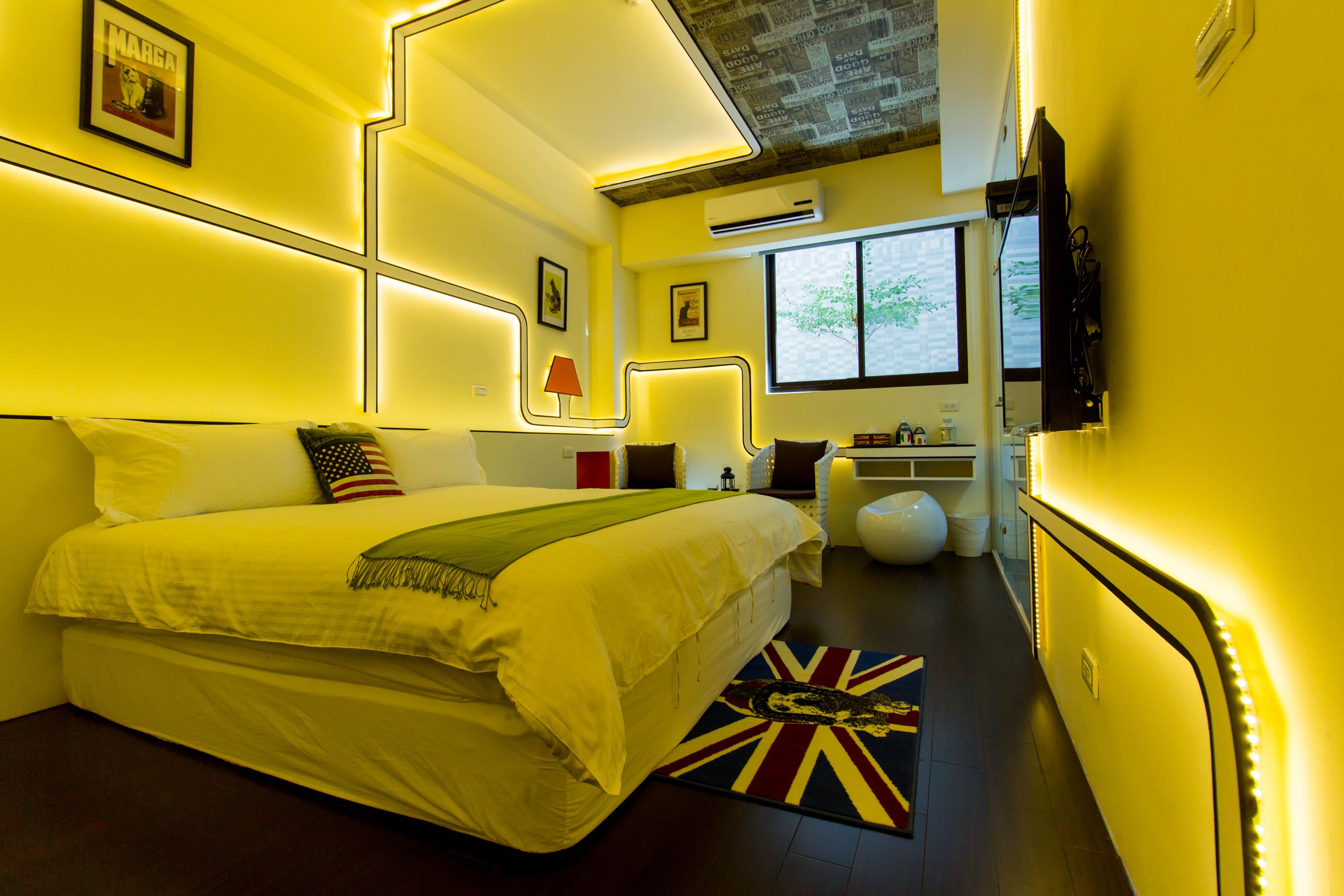 Una habitación de hotel moderna con una cama grande, mesitas de noche, un escritorio y un televisor.