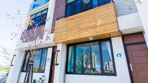 A modern multi-story building with large windows, a wooden balcony, and potted plants on the ground floor. - F One B&B (Wujie)