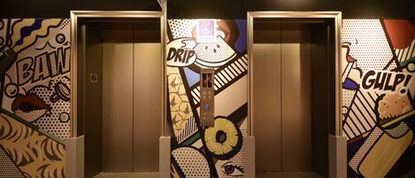 An elevator with a colorful, abstract mural on the walls and a sign that reads "DRIP."