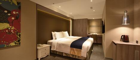 Une chambre d’hôtel moderne, dotée d’un grand lit, d’une table de chevet et d’un espace bureau.
