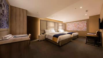 Une chambre d’hôtel avec un grand lit, un bureau avec une chaise, une petite table et un fauteuil massant.