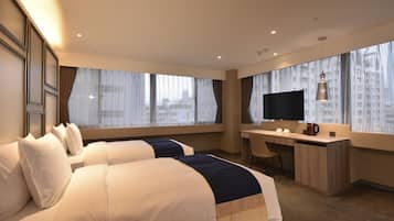 A hotel room with two beds, a desk, a chair, a television, and large windows with sheer curtains.