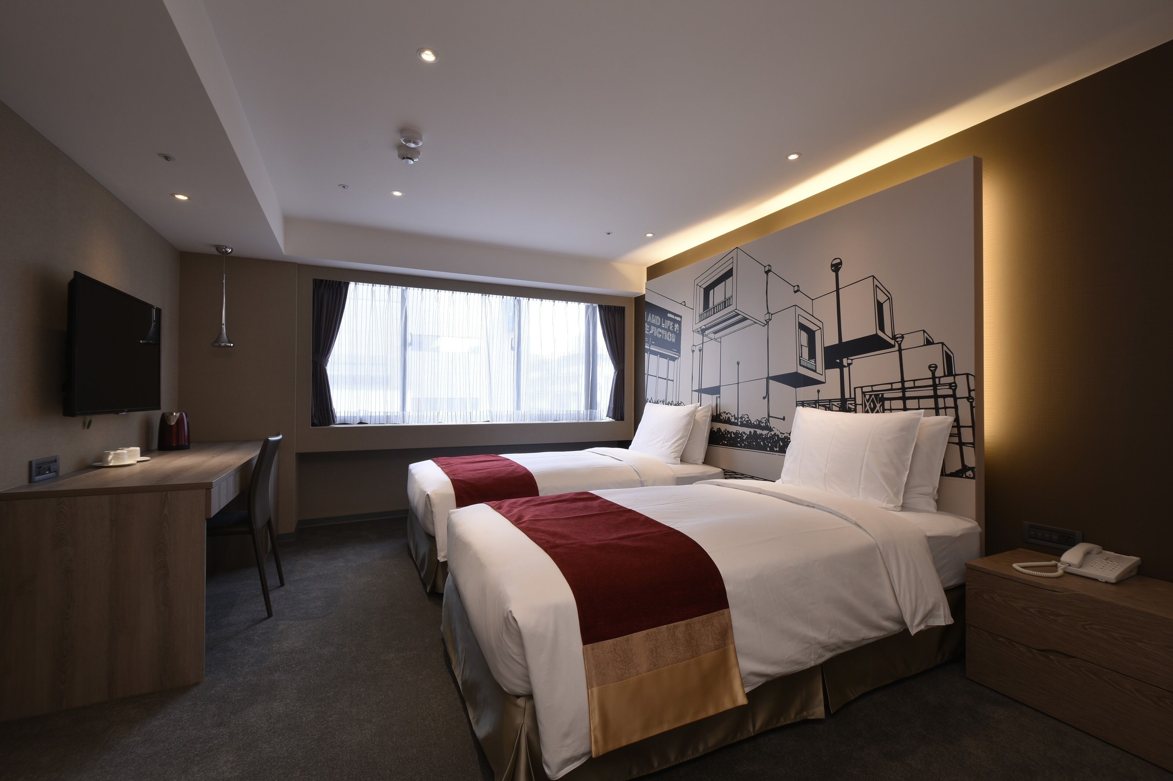 A hotel room with two beds, a desk, a chair, a TV, and a large window with curtains.