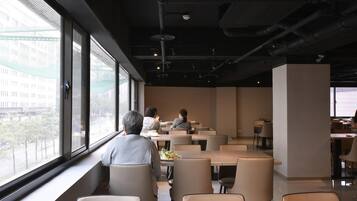 Un comedor moderno con ventanas amplias, mesas y sillas.