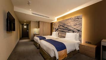 Une chambre d’hôtel avec deux lits, un téléviseur à écran plat fixé au mur, une table de chevet en bois et une grande fresque abstraite sur le mur.