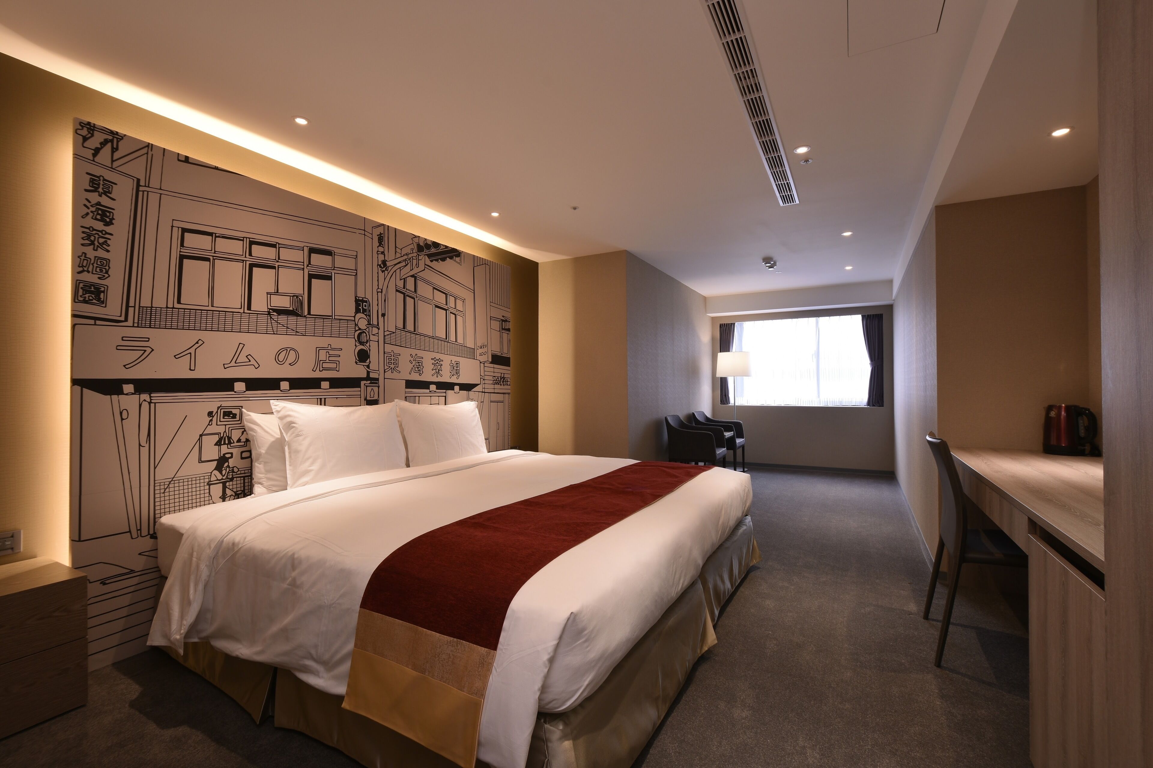 Habitación de hotel con una cama grande, un escritorio y una silla. Se ve una ventana con cortinas y una pared con un mural.