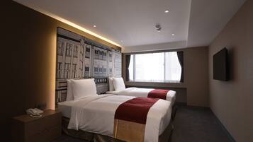 A hotel room with two beds, a large window, a mounted TV, and a wall mural.