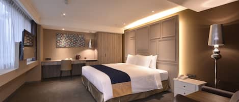 Habitación de hotel con una cama grande, un escritorio, una silla, una lámpara y vistas a la ciudad.