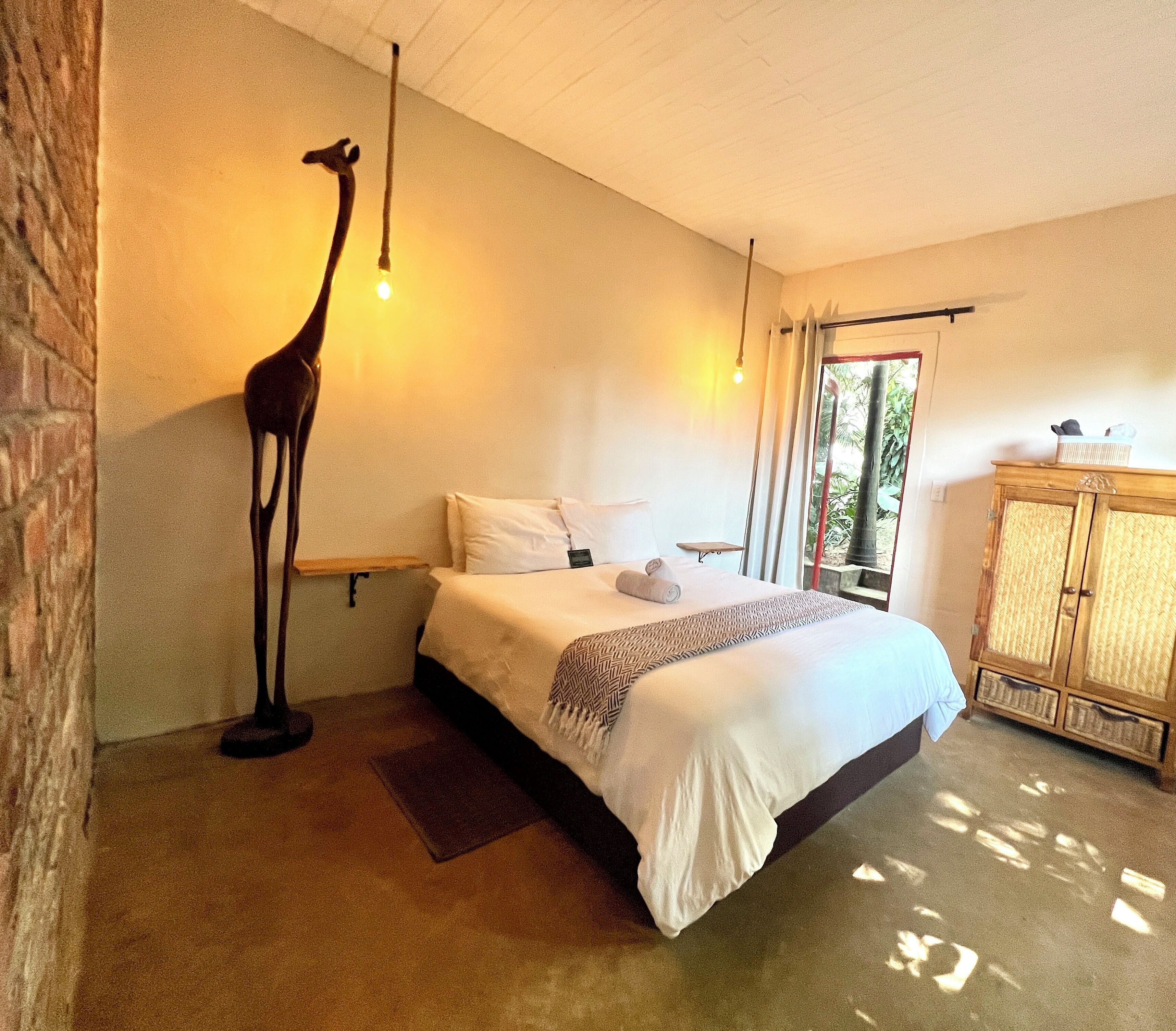 Una camera da letto con un letto, una scultura di giraffa, una finestra e un armadio in legno.