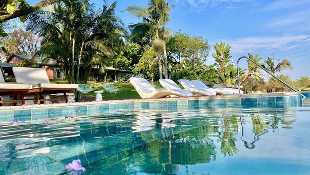 A pool area with lounge chairs and a view of the surrounding greenery. - LoerieRoep (Mbombela)