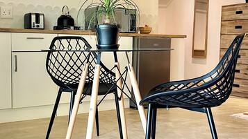 Una cocina moderna con una mesa de comedor, dos sillas, una planta en maceta y un microondas.