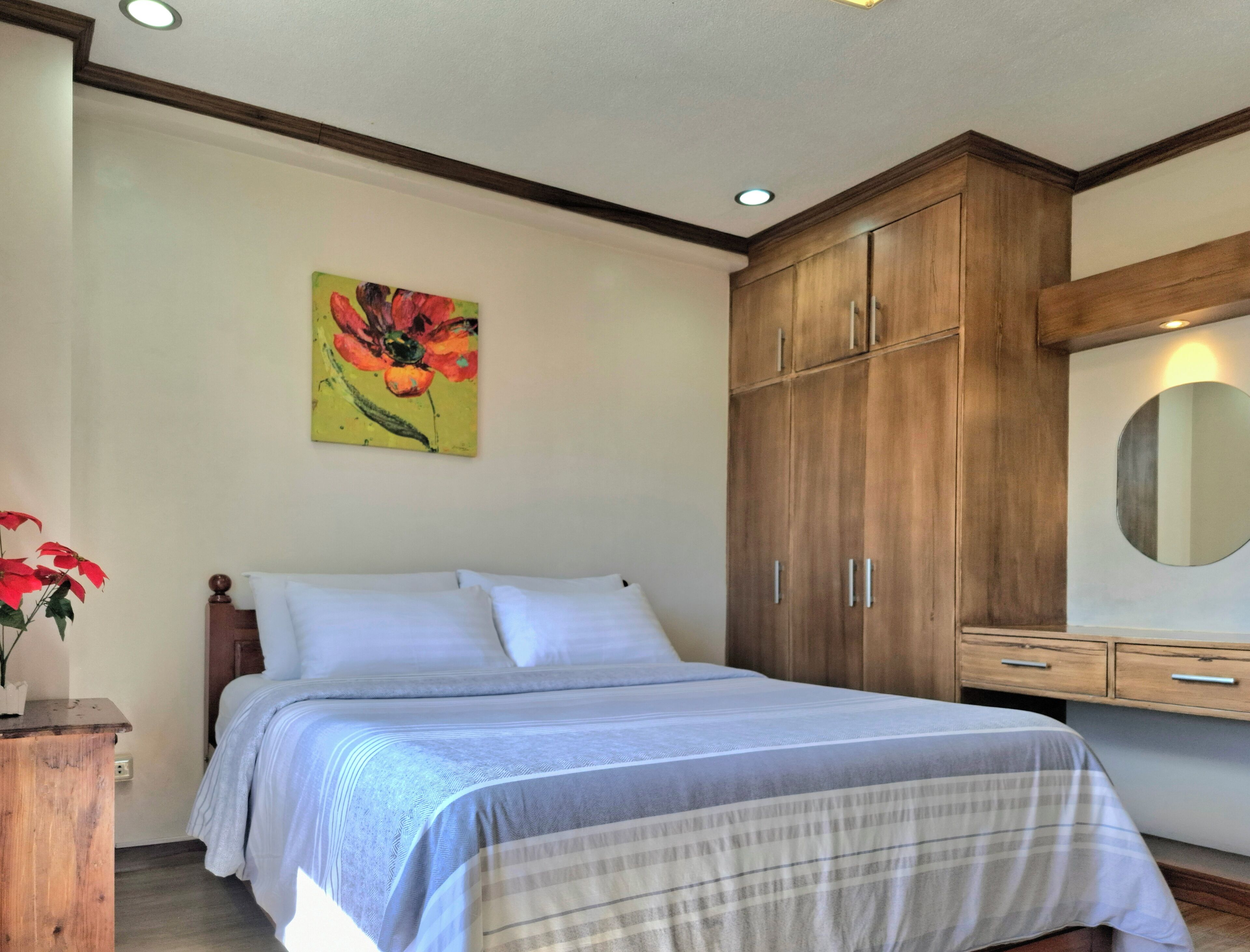 Une chambre à coucher avec un lit, une armoire en bois et un tableau accroché au mur.