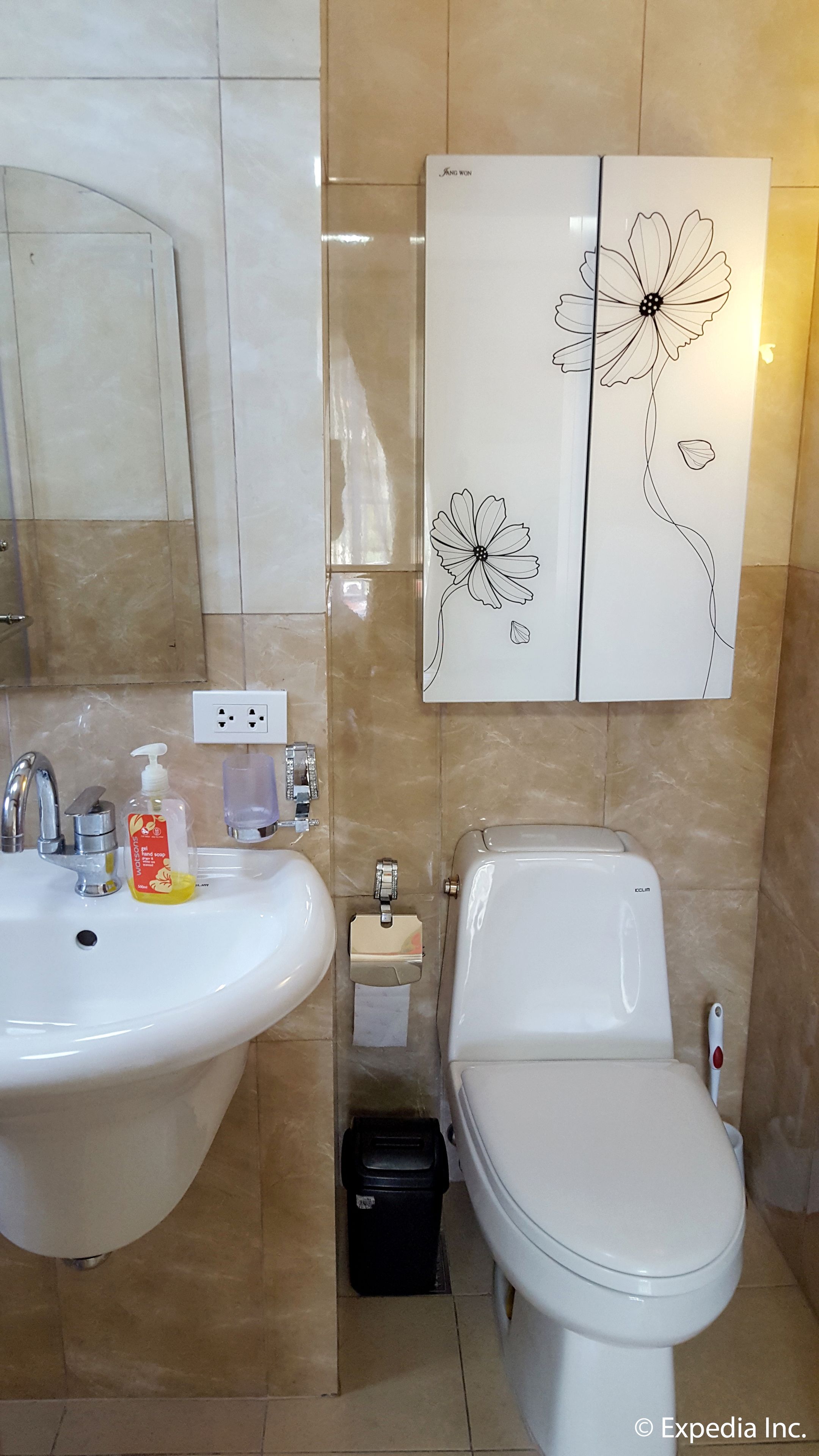 Une salle de bain équipée d’un lavabo, de toilettes et d’une œuvre d’art représentant des fleurs, accrochée au mur.