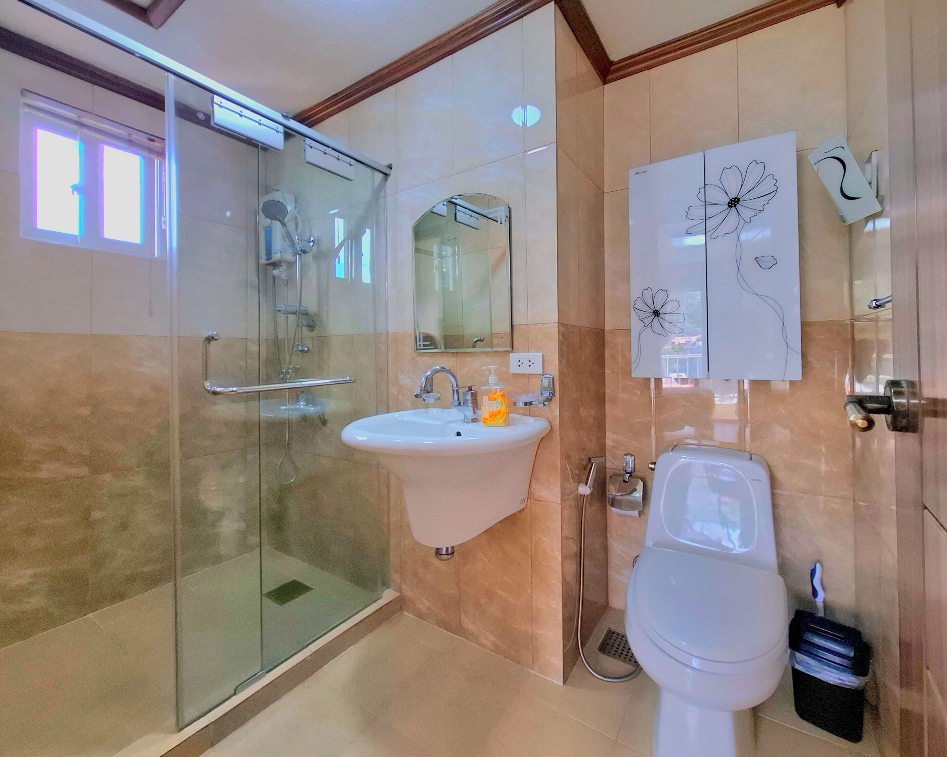 Een moderne badkamer met een douchecabine van glas, een witte wastafel en een toilet.
