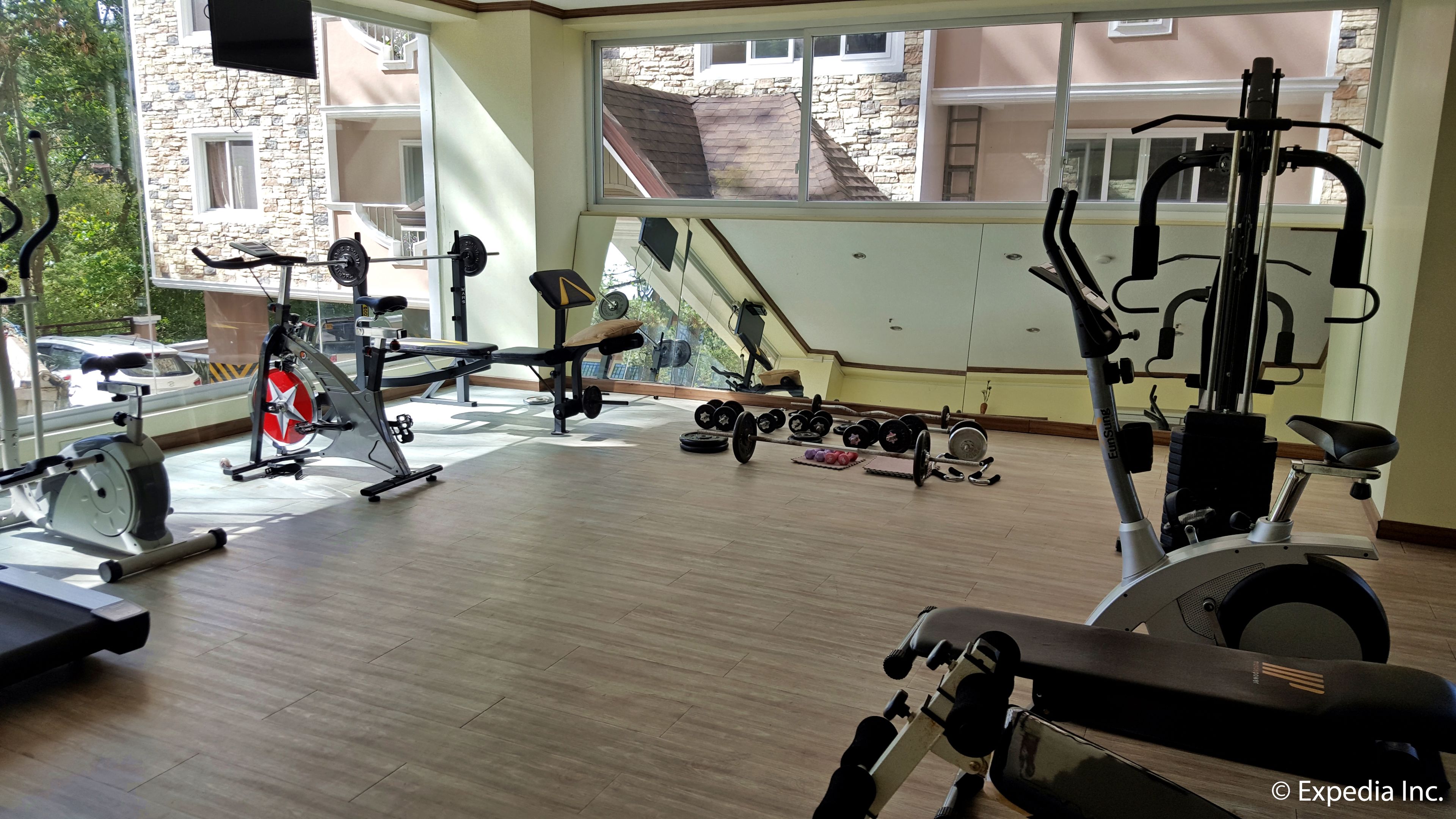 Un gimnasio con diversos equipos de ejercicio, incluyendo cintas de correr, bicicletas estáticas y pesas libres.