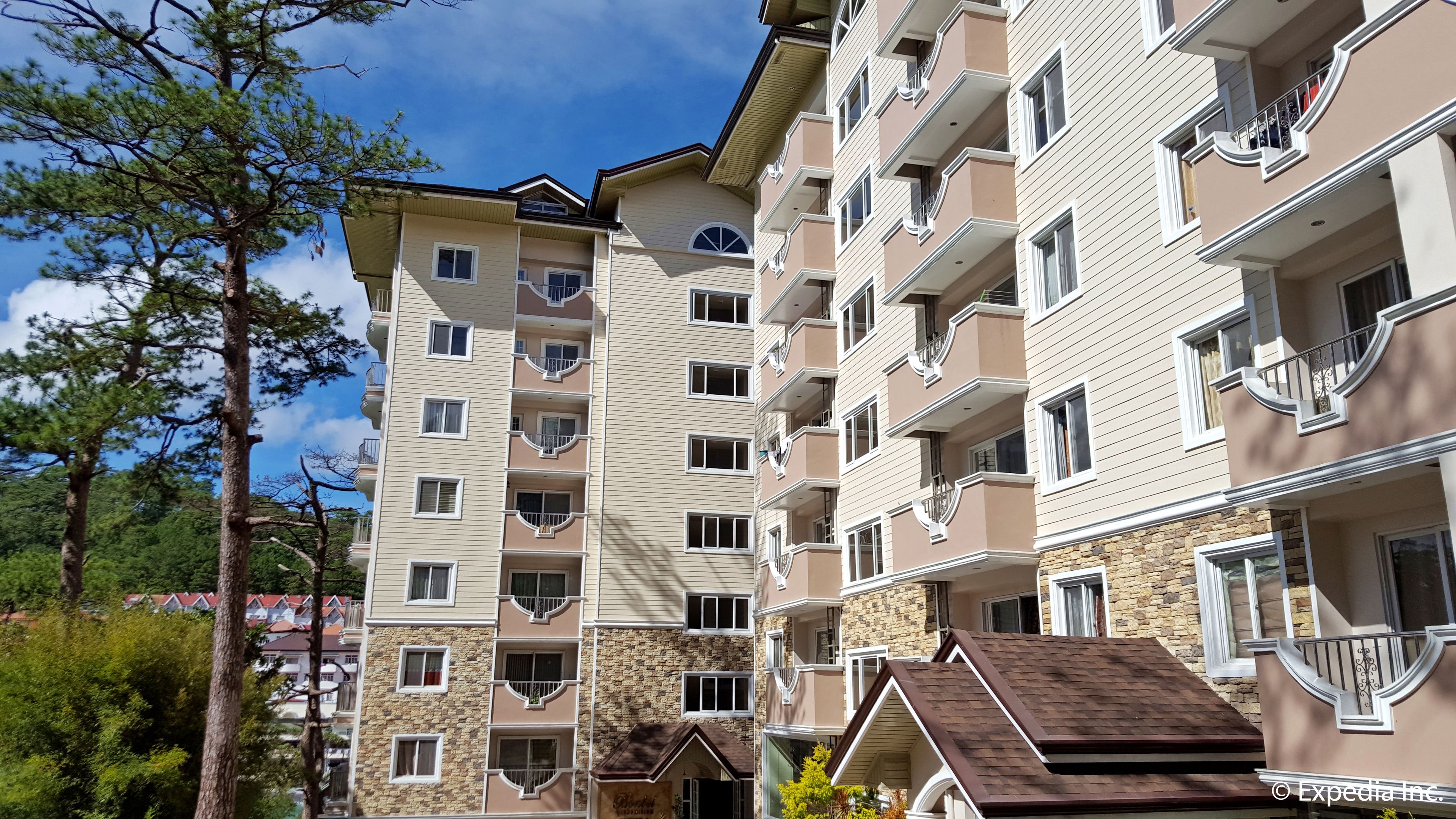 Un hotel de varios pisos con balcones, detalles de piedra y un cielo despejado.