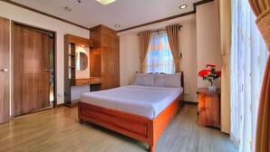 A bedroom with a wooden bed, a wardrobe, a bedside table, and a window with curtains. - Prestige Vacation Apartments - Bonbel Condominium (Baguio)