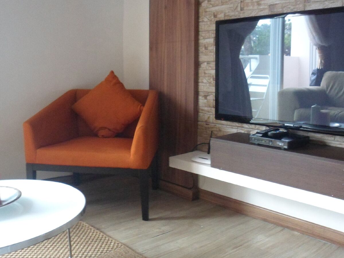 Un salon moderne avec un canapé, un téléviseur à écran plat et une petite table.