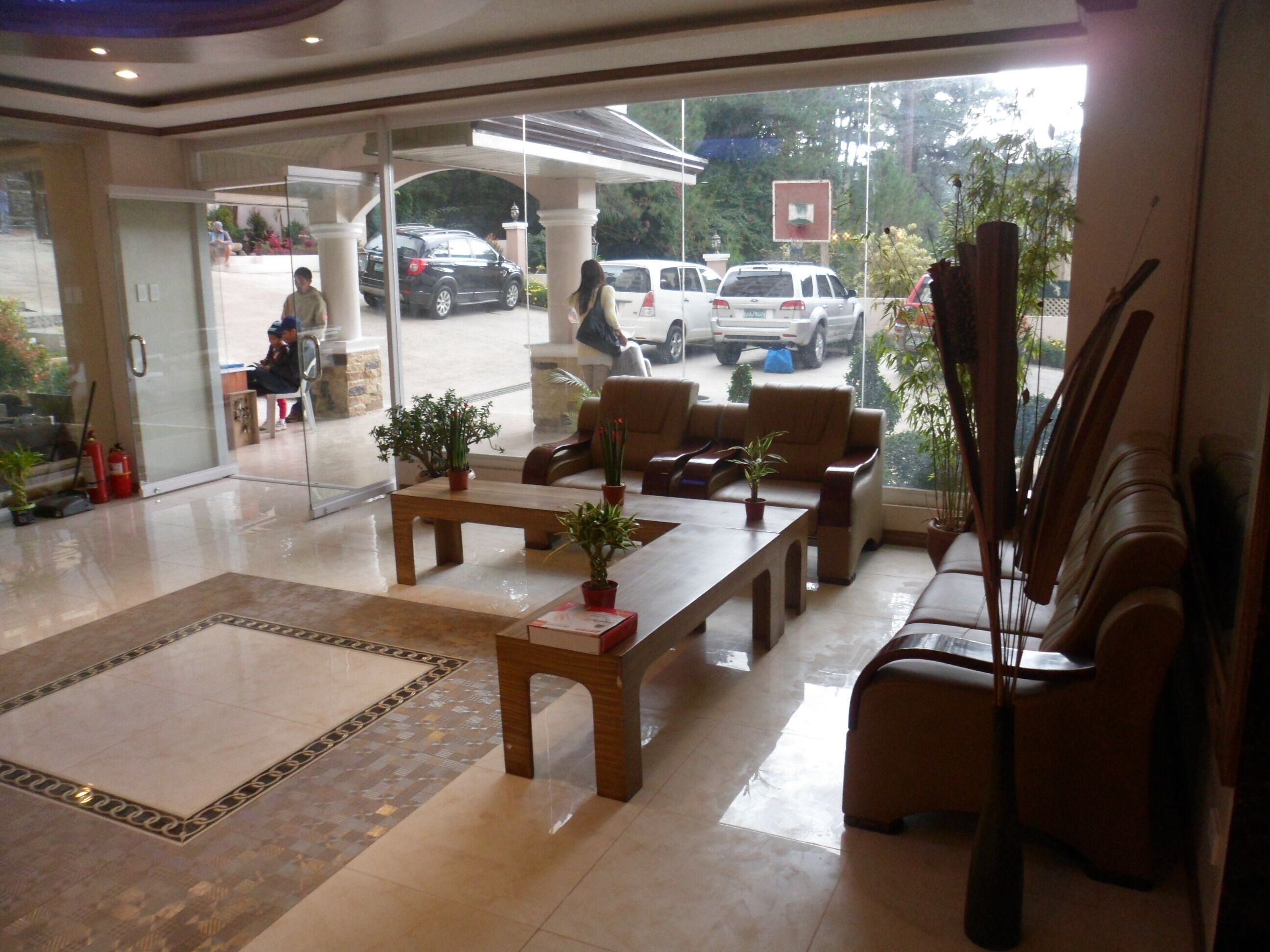 A lobby with a reception desk, seating area, and a view of parked cars outside.