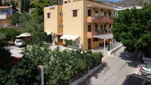 A two-story hotel with a yellow facade, balconies, and a patio area. - Katerina Hotel (Nafplio)