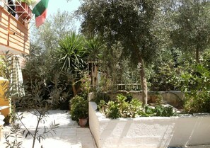 A garden with various plants and a white wall. - Katerina Hotel (Nafplio)